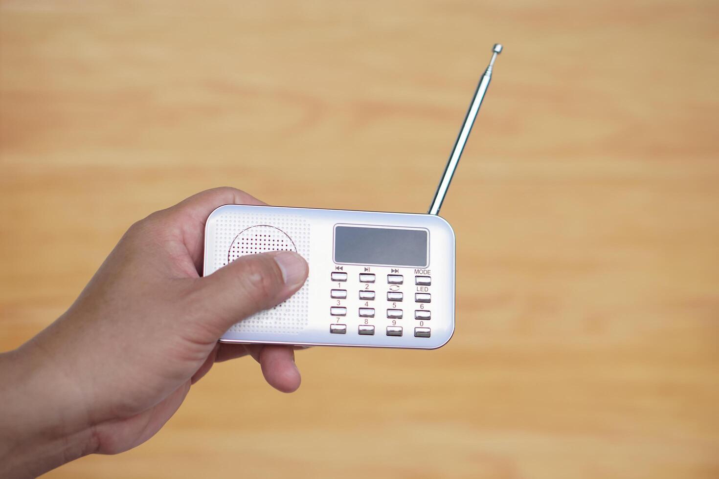 Hands hold portable mini radio. Concept, audio electronics for listening to music, songs or news from radio wave channel station. Analog amplifier for relaxation and lifestyle. photo