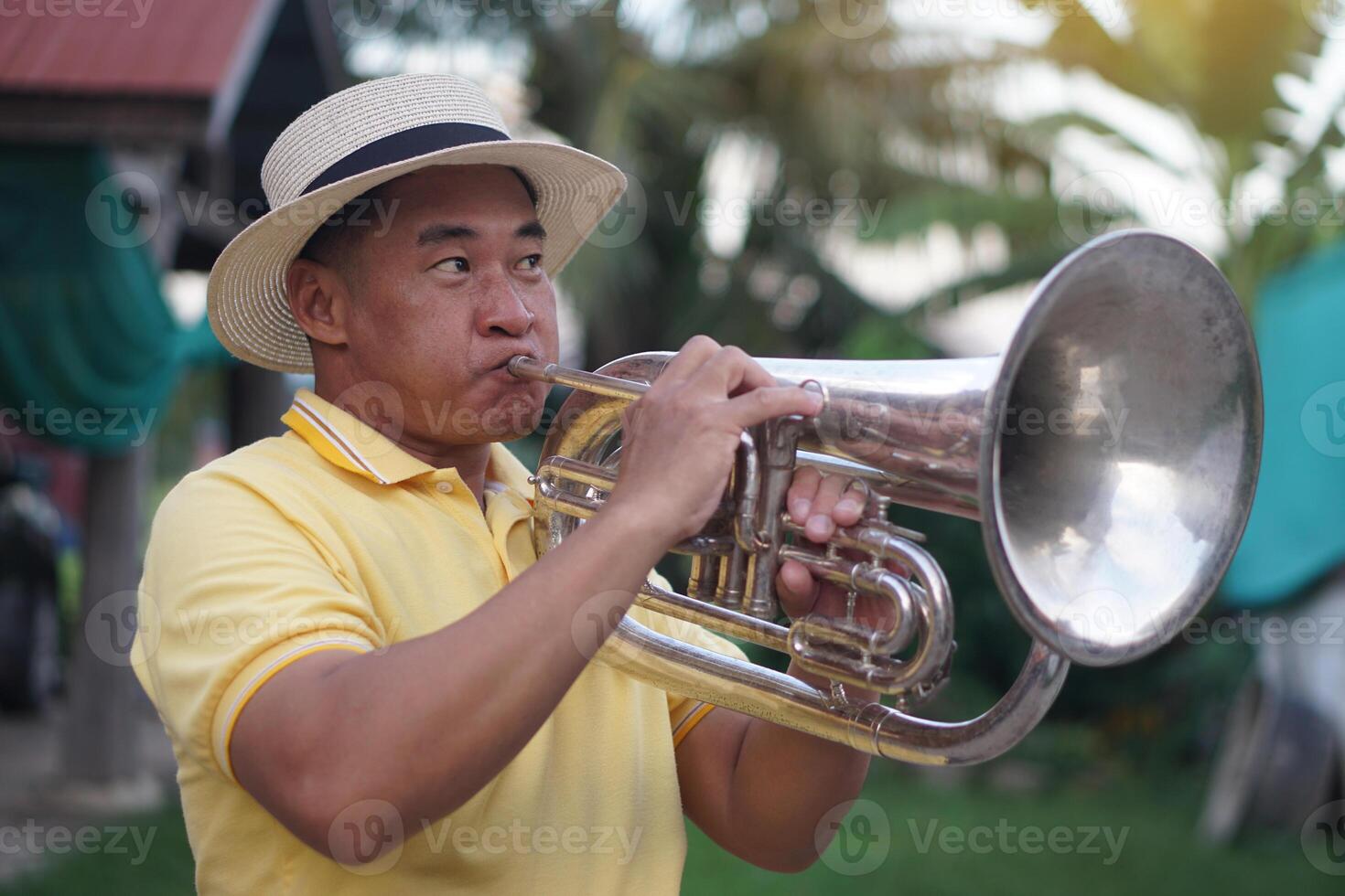 Asian man is playing the euphonium. Concept, love music, hobby, recreation activity. Relax time. Lifestyle. Music can develop mental health. Mouthpiece musical instrument. Rehearsal music. photo