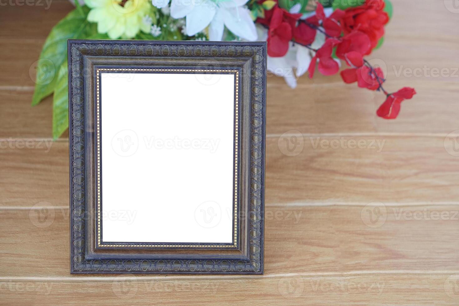 Photo frame on wooden floor, decorated with flowers behind. Copy space for adding text or photos. Concept, Proud, memories and nostalgia. Exhibition, art gallery. Photography.
