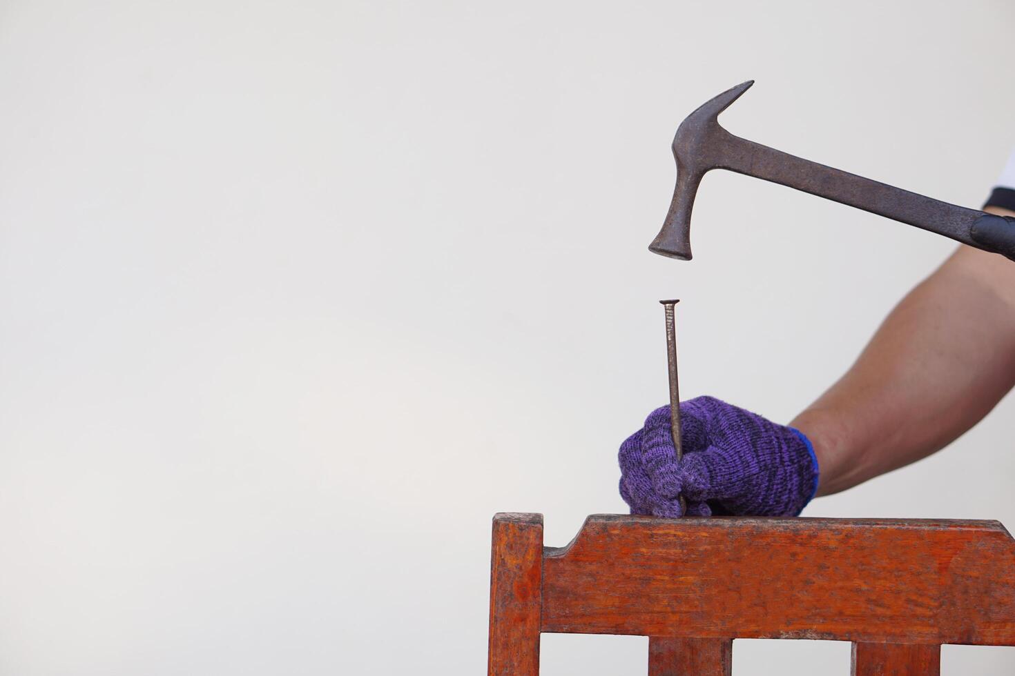 Closeup carpenter hand uses hammer to hit nail. Concept, carpentry and construction tools. Repair or fixing, DIY woodwork. photo