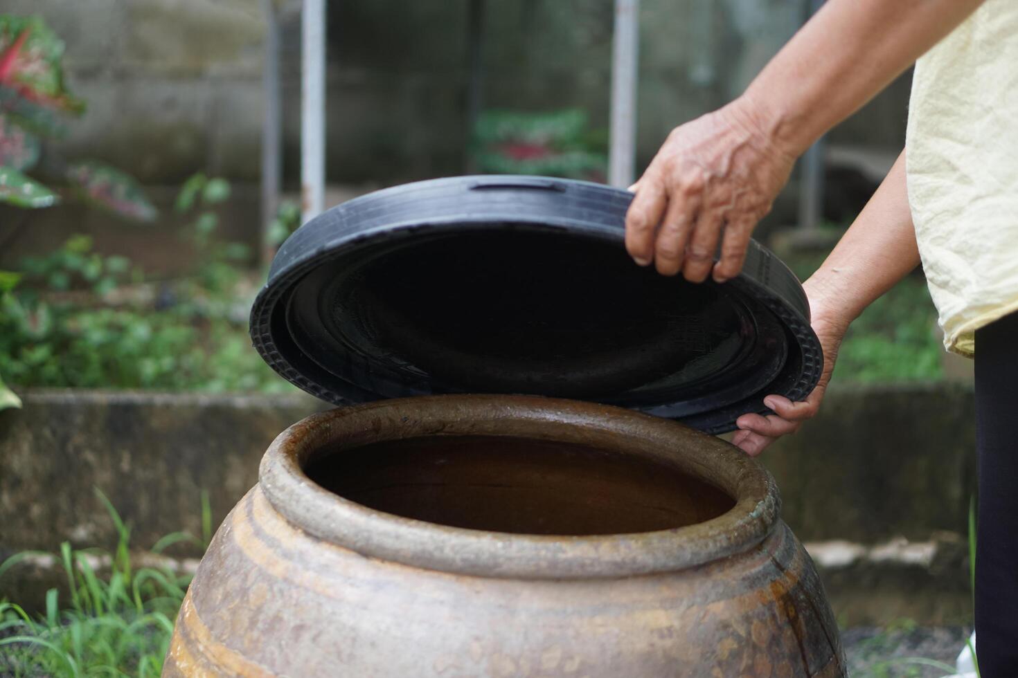 Closeup hands hold lid to cover water jar to protect from mosquitoes to breed inside or other insects or dust go into water. Concept, campaign to stop mosquitoes cycle to lay eggs in water container photo