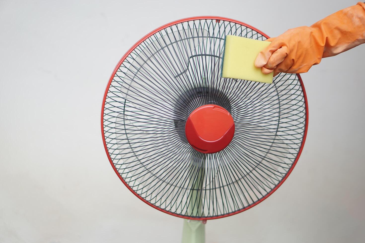 Close up hands wear gloves, hold sponge to clean electric fan. Concept, Appliance maintenance and repair for long using. Clean dust on fan to stop allergy for hygiene. Chore and household keeping. photo