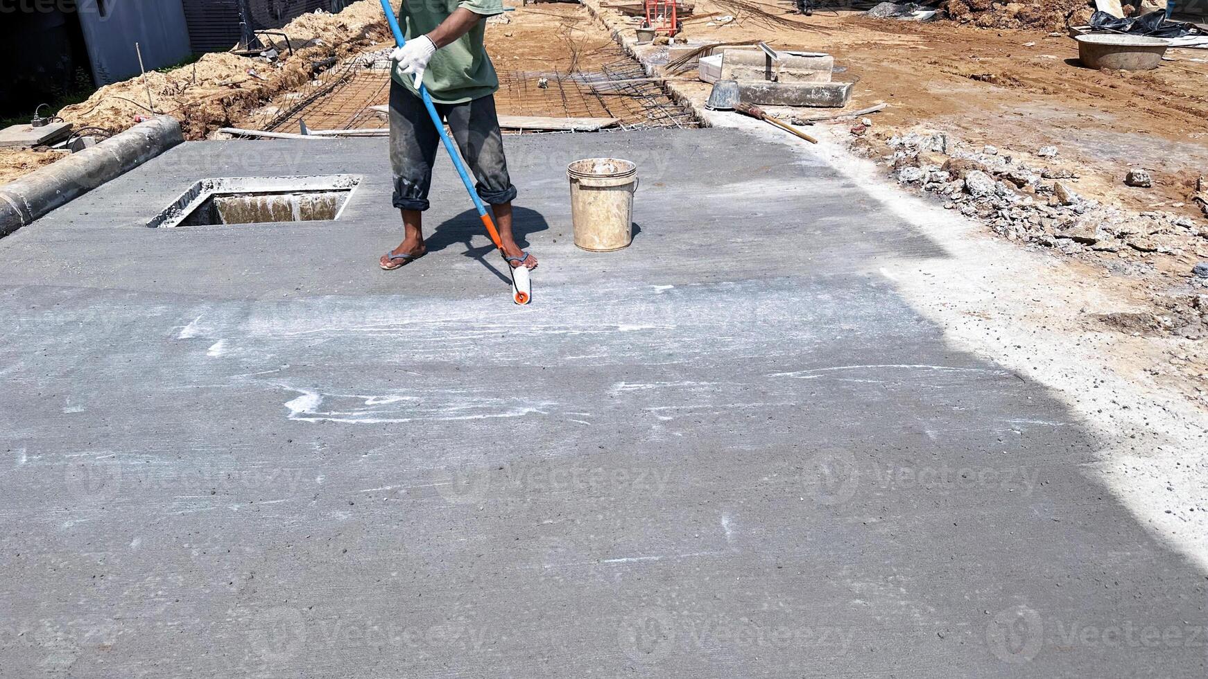 Technician applies concrete curing agent to prevent cracking. concrete primer Steps for applying foundation with a roller on concrete floors Primer for strengthening the surface. photo