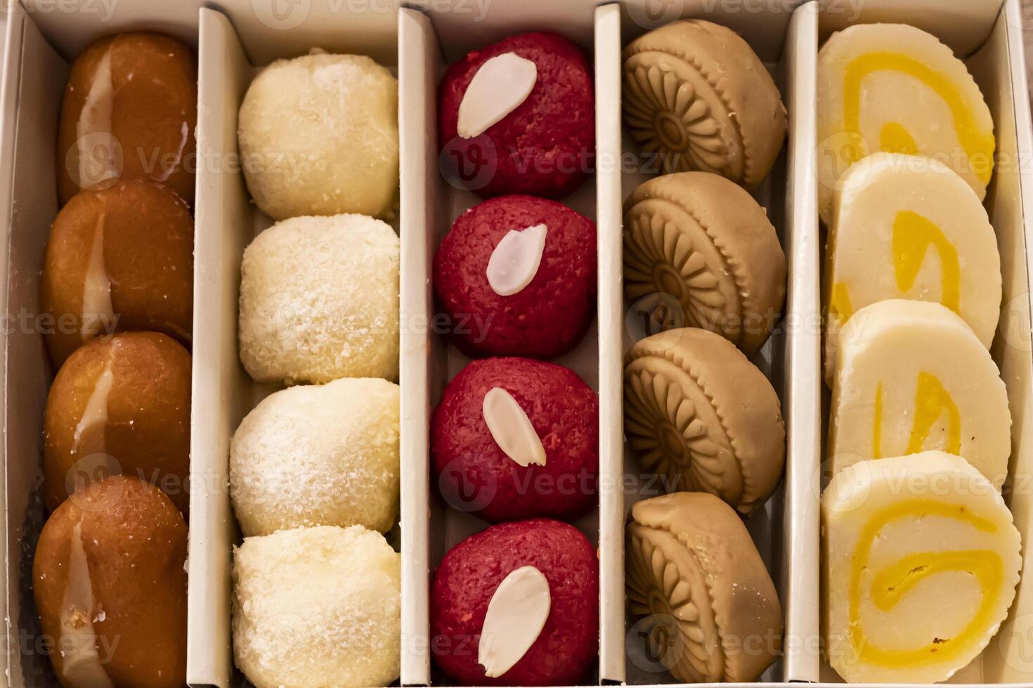 Assorted indian sweet box include Cream Gulab Jamun, Motichoor Laddu, GURER SONDESH, Cake Barfi, Balushai, Balushahi top view of pakistani and bangladeshi mithai dessert photo