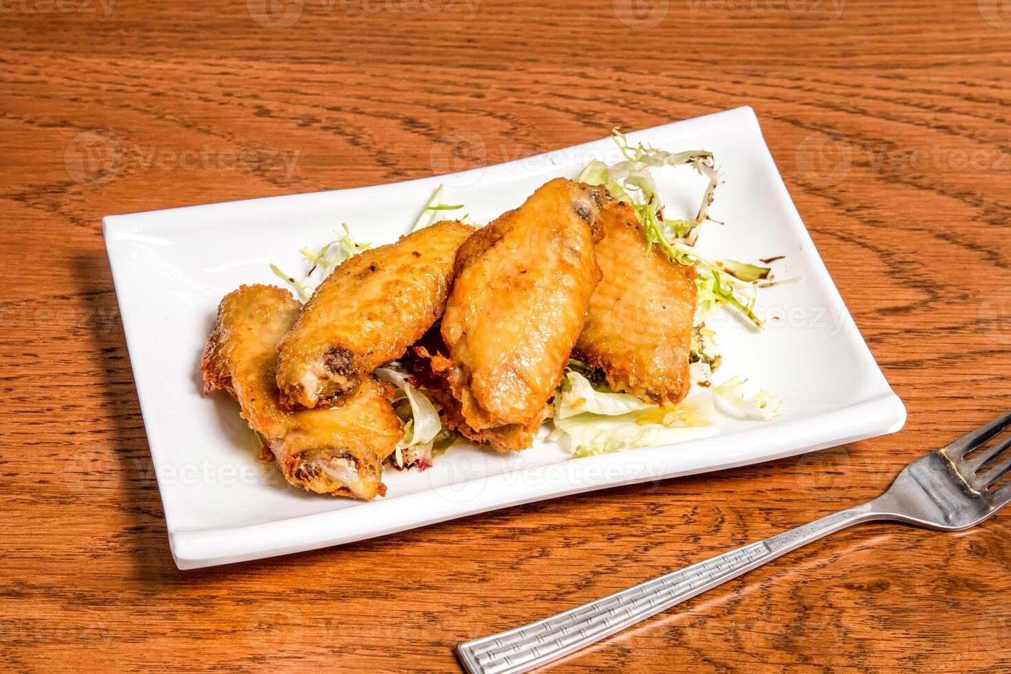 Lemon honey chicken wings with cabbage served in tray dish with fork isolated on wooden table side view of fast food photo