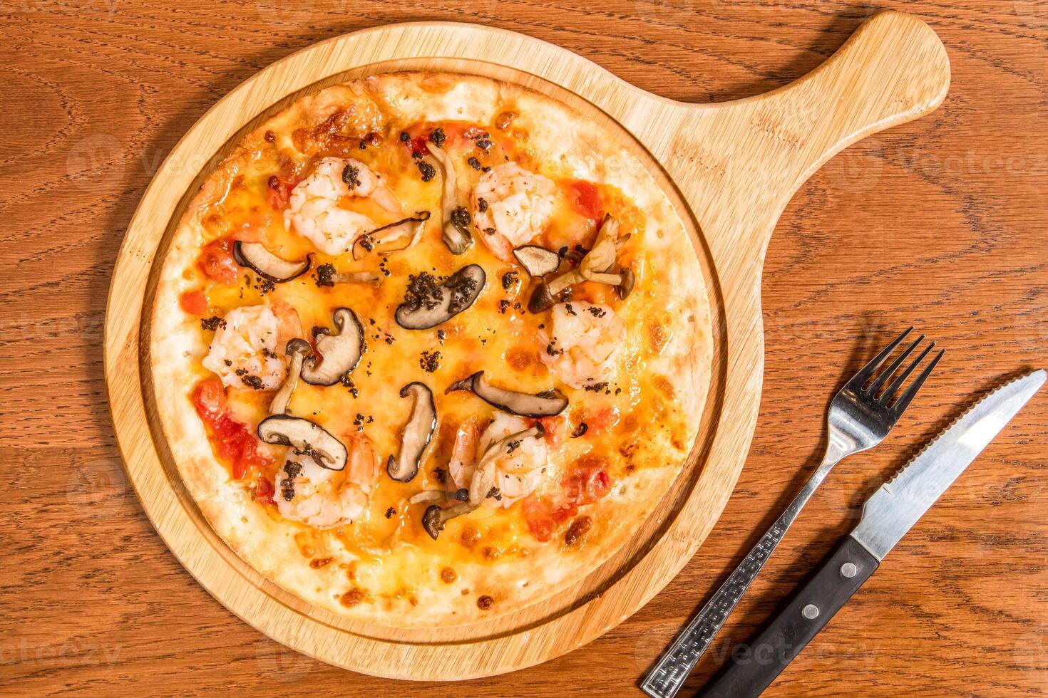 Black Truffle Mushroom and Shrimp Pizza served on wooden board with knife and fork isolated on table top view of italian cousin photo