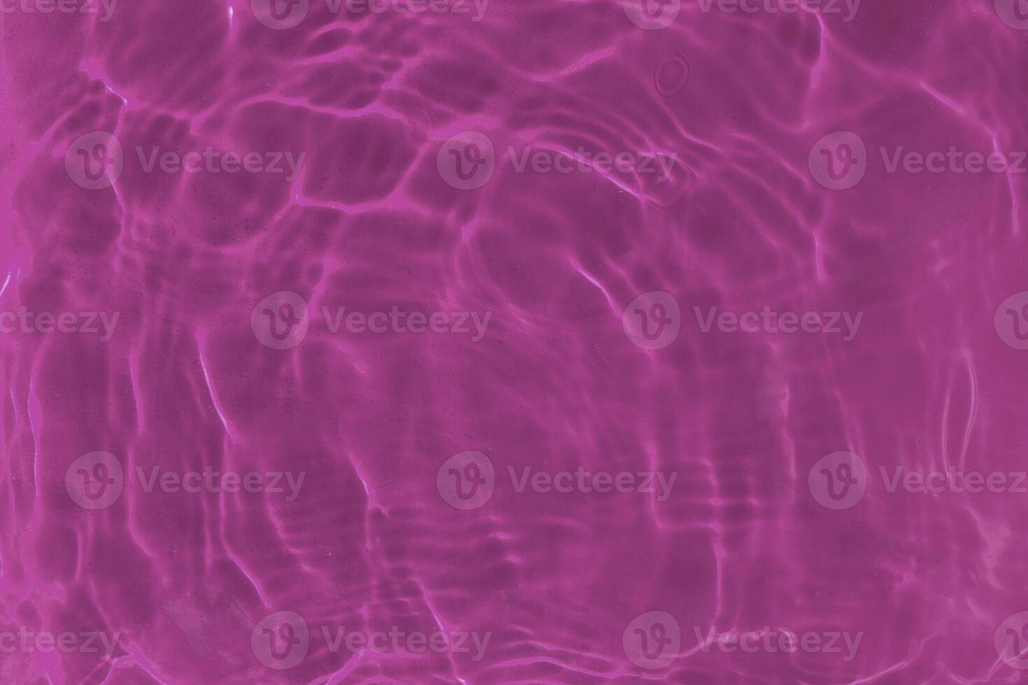 Transparent pink clear water surface texture with ripples, waves and rings in sunlight. photo