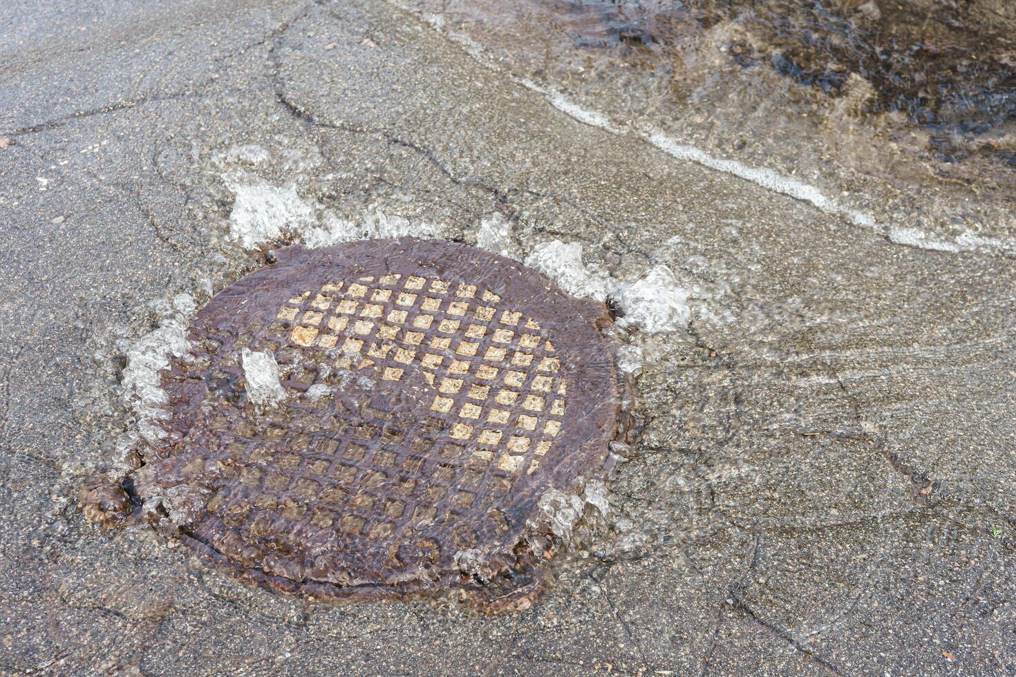 Water fountain pours out from sewer hatch, breakthrough sewerage system, accident of water supply photo