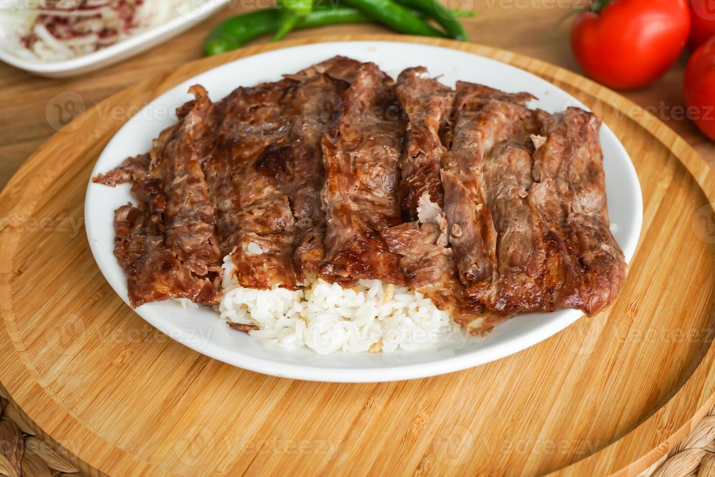 Meat Doner Kebab on Rice portion served in tray dish with garlic, tomato, and green chilli isolate on wooden board top view of arabic and turkish fast food photo