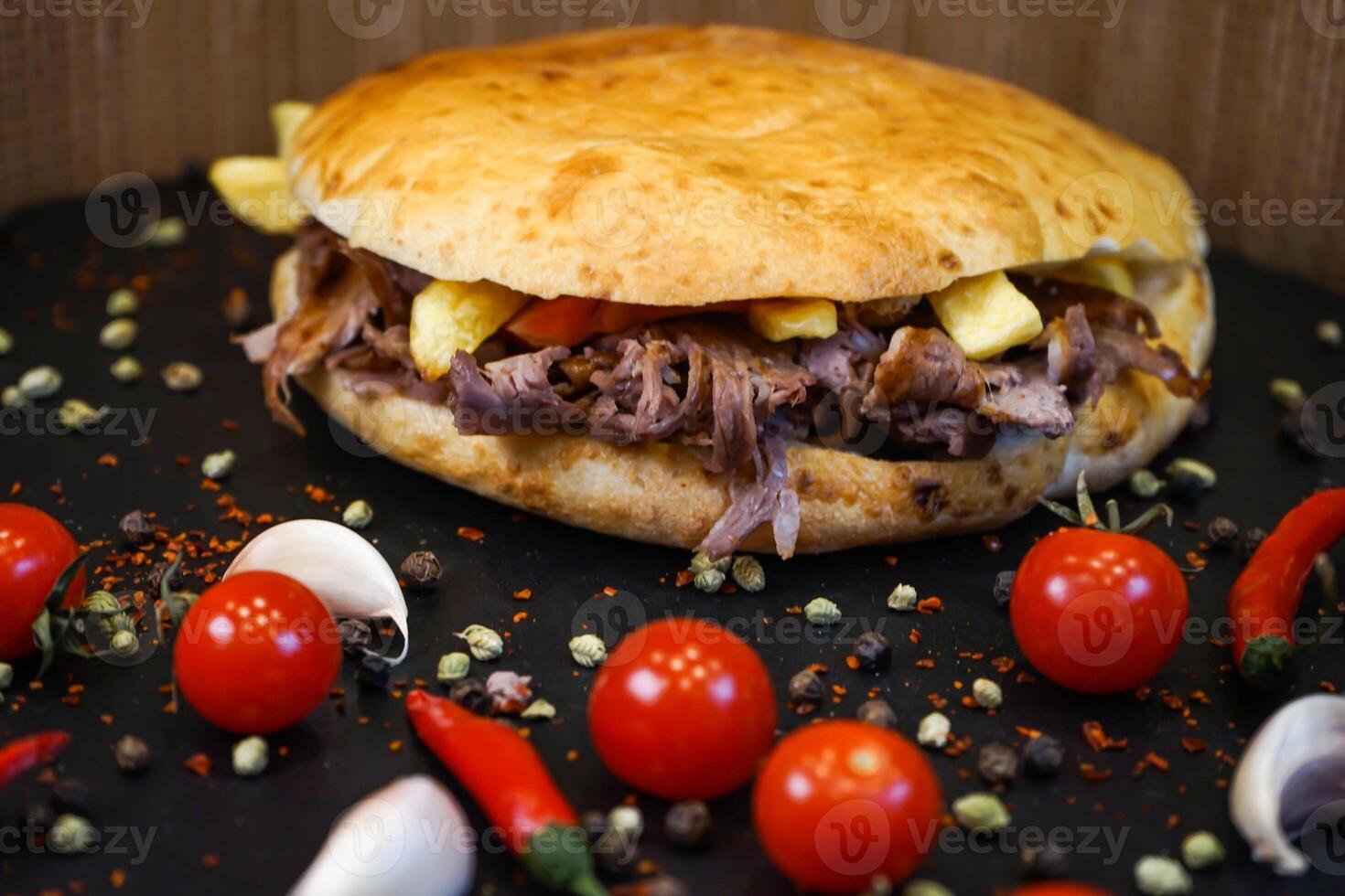 Meat Tombik Doner Kebab Sandwich with tomato, garlic, red pepper isolated on dark background side view of turkish fast food photo