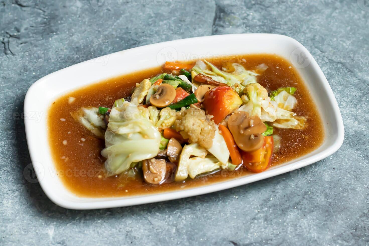 Mixed Stir fry Vegetables including cabbage, cauliflower, mushroom, carrot, tomato and green chilli served in tray dish isolated on grey background side view of thai food photo