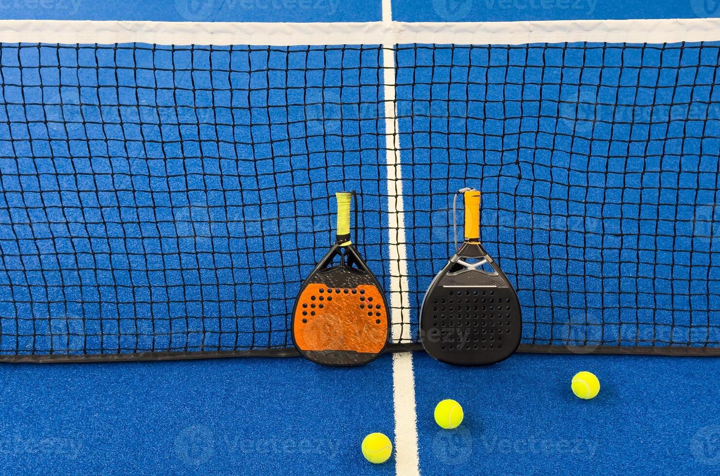 Black professional paddle tennis racket and ball with natural lighting on blue background. Horizontal sport theme poster, greeting cards, headers, website and app photo