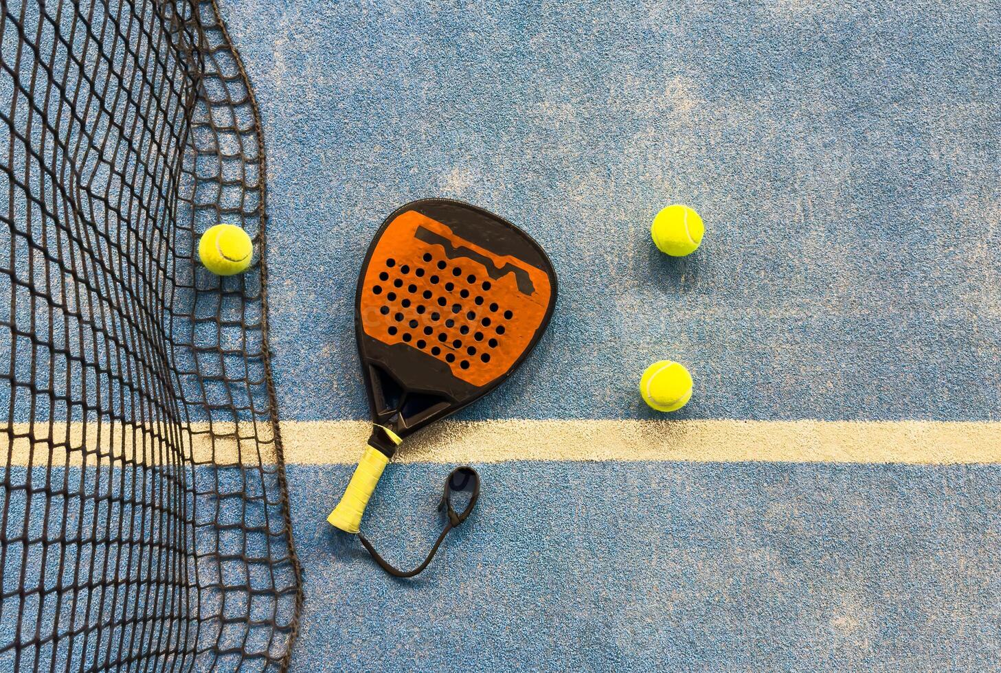 Black professional paddle tennis racket and ball with natural lighting on blue background. Horizontal sport theme poster, greeting cards, headers, website and app photo