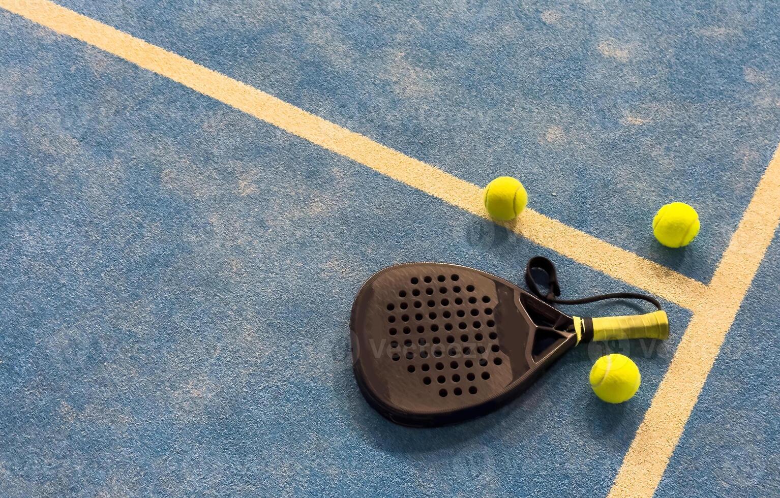 Black professional paddle tennis racket and ball with natural lighting on blue background. Horizontal sport theme poster, greeting cards, headers, website and app photo
