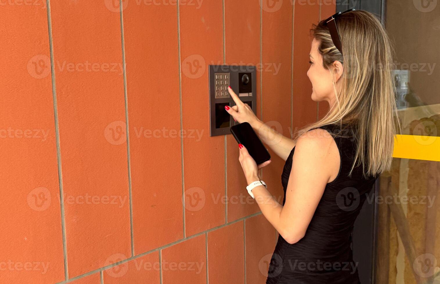 female entering secret key code for getting access and passing building using application on mobile phone, woman pressing buttons on control panel for disarming smart home system photo