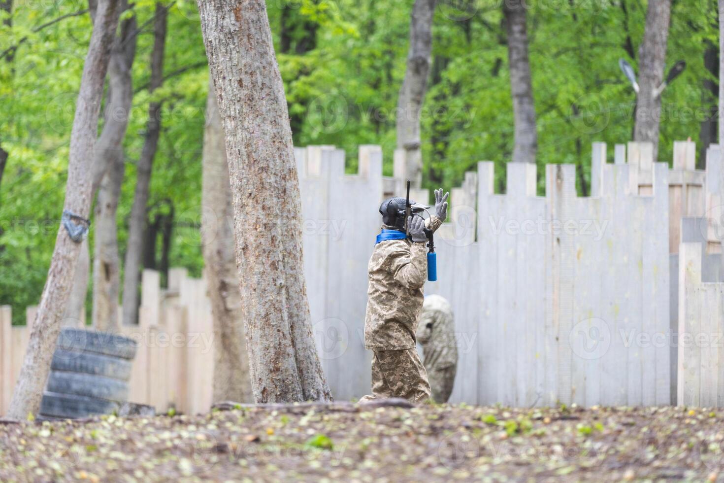 Paintball game. Players with weapons shooting paint balls. Men on the playground. Guys in camouflage and masks are fighting. photo