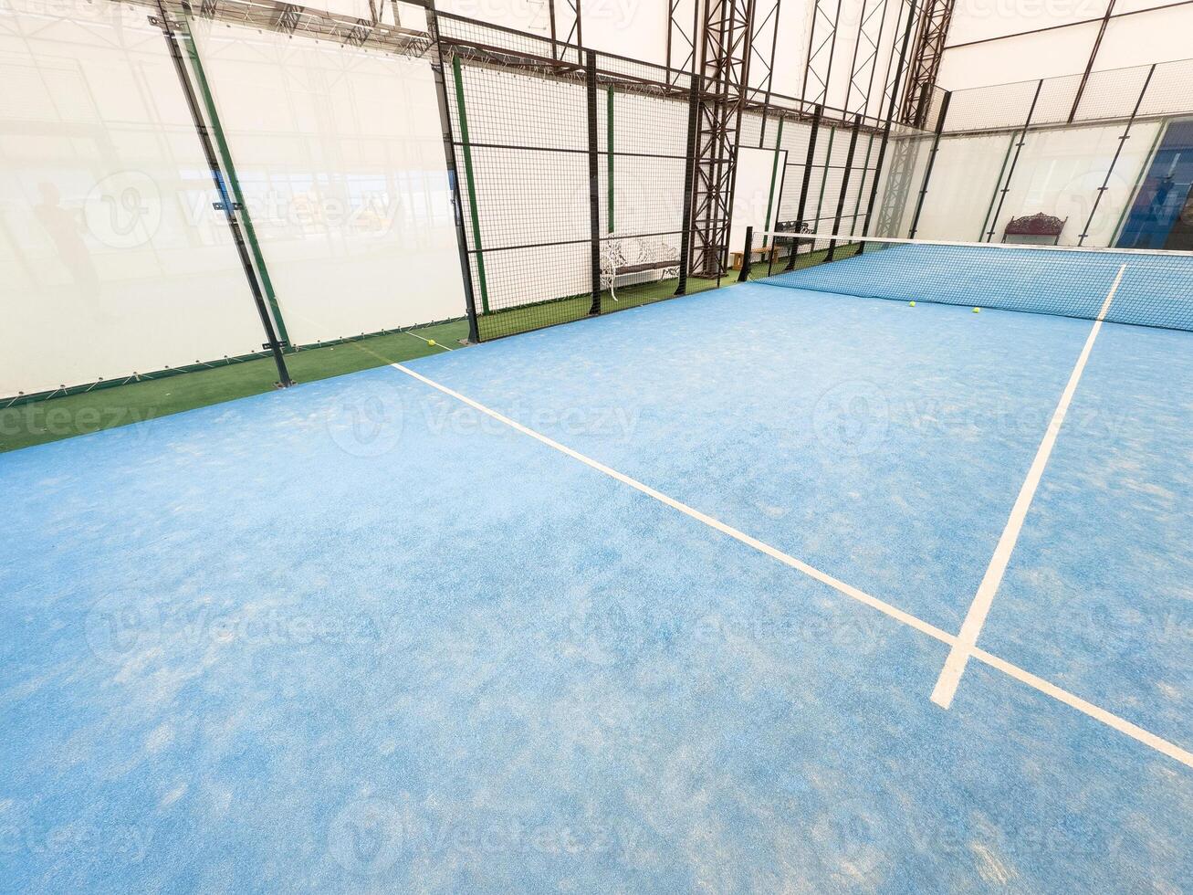 empty paddle tennis court with lights on in a covered shed with no players photo