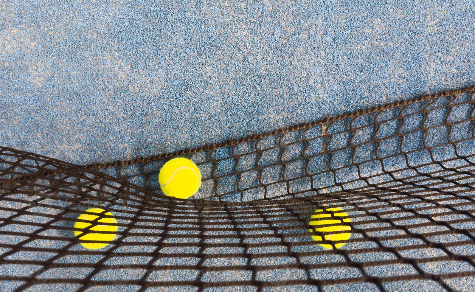 Ball in the shade of the net of a blue paddle tennis court. photo