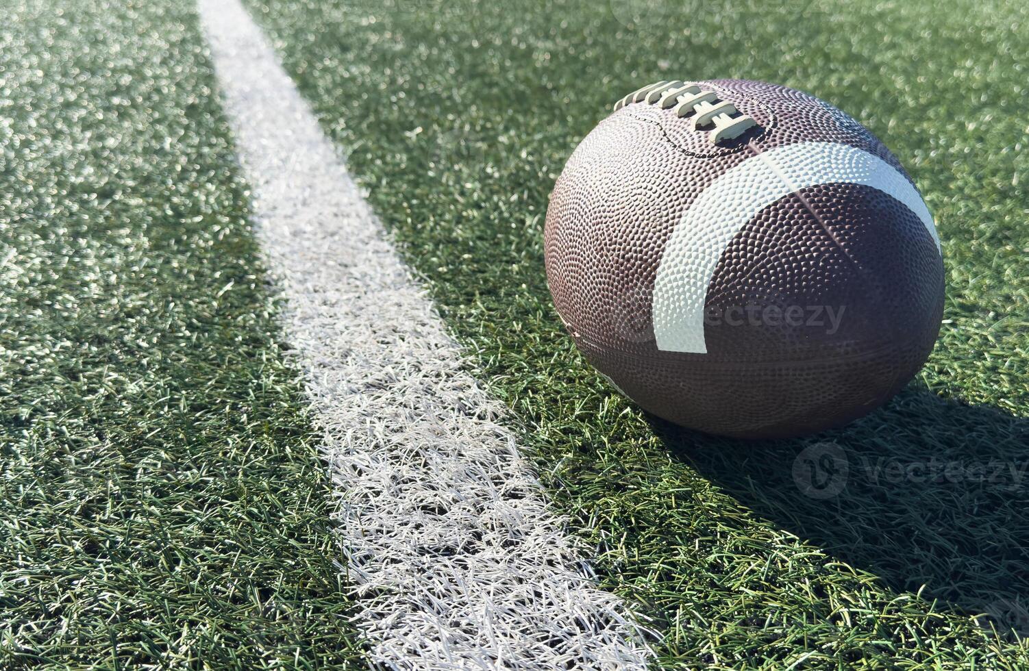 Close up of an american football on the field, players in the background photo