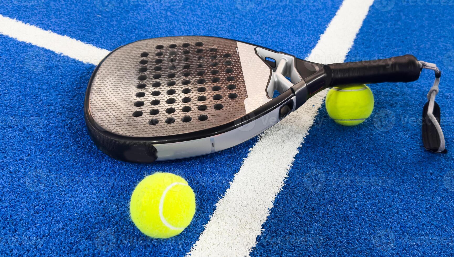 Paddle racket with a ball ready to play the fastest growing sport in recent years worldwide. Padel court in summer, the perfect time to practice this sporting discipline and release stress. photo