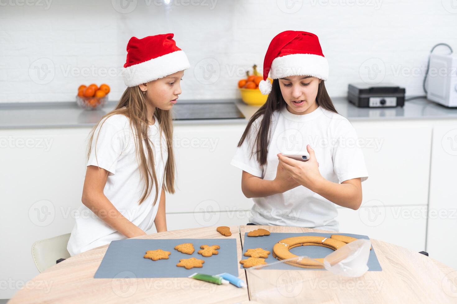 Two girls sisters are playing around in the kitchen after making Christmas cookies, they draw with flour on the table and on their faces. Christmas, New Year concept photo