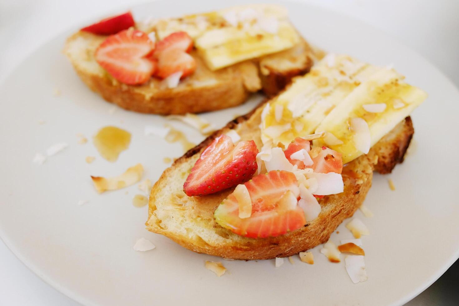 Homemade fresh strawberries with banana and cream cheese on wheat bread with honey and almond peanut topping. French almond toast delicious breakfast or dessert photo