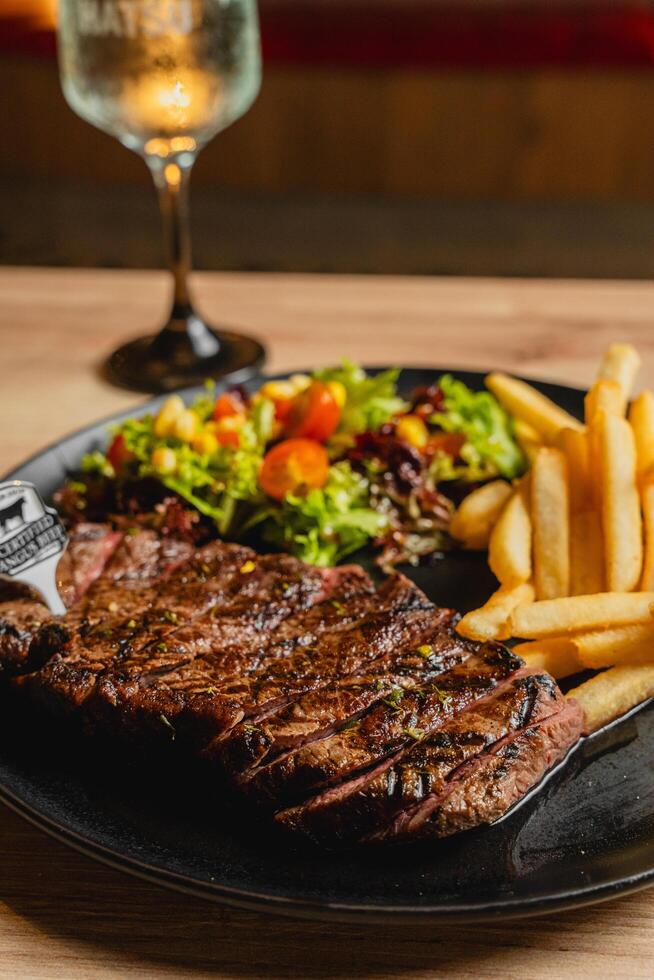 Lunch featuring a steak filet, salad, and French fries, elegantly presented on a table. photo