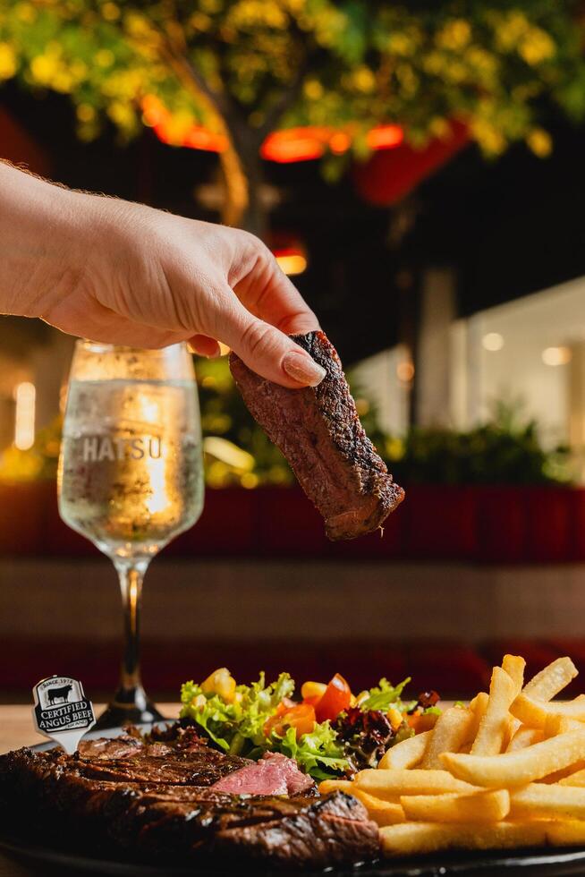 Lunch featuring a steak filet, salad, and French fries, elegantly presented on a table. photo