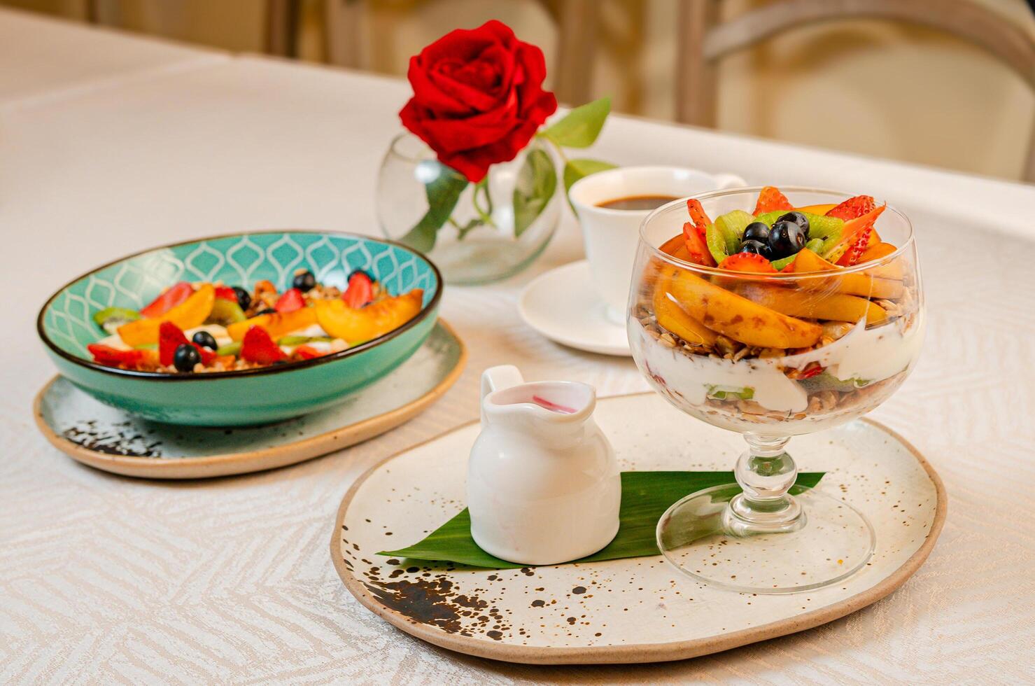 A breakfast table featuring coffee, orange juice, fruits, a gourmet plate with toast, burrata, serrano ham, tropical fruits, and traditional Caribbean fried snacks photo