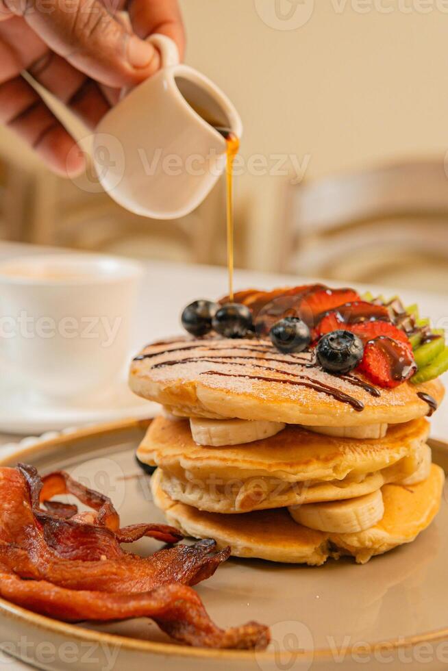 A breakfast of pancakes drizzled with honey, served with crispy bacon photo