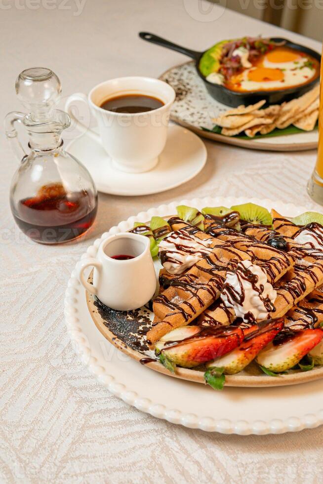 Fruit crepes with chocolate and maple syrup for breakfast photo