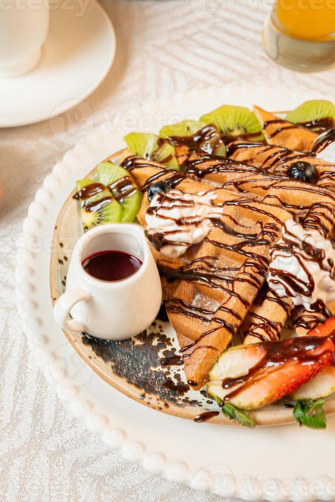 Fruit crepes with chocolate and maple syrup for breakfast photo