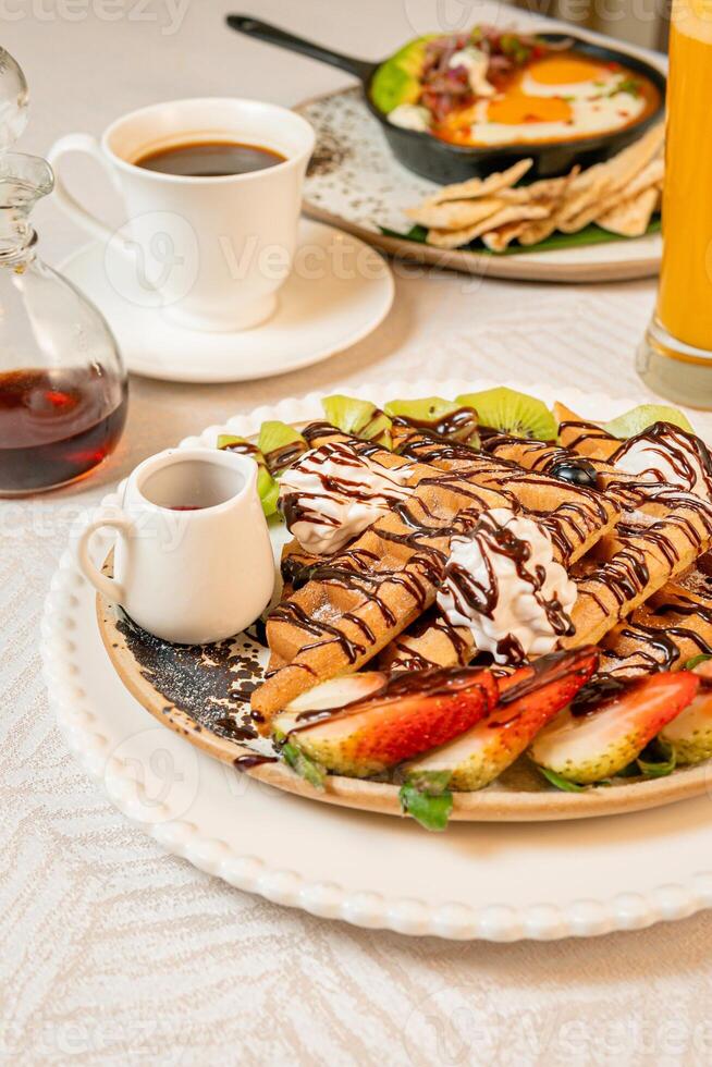 Fruit crepes with chocolate and maple syrup for breakfast photo