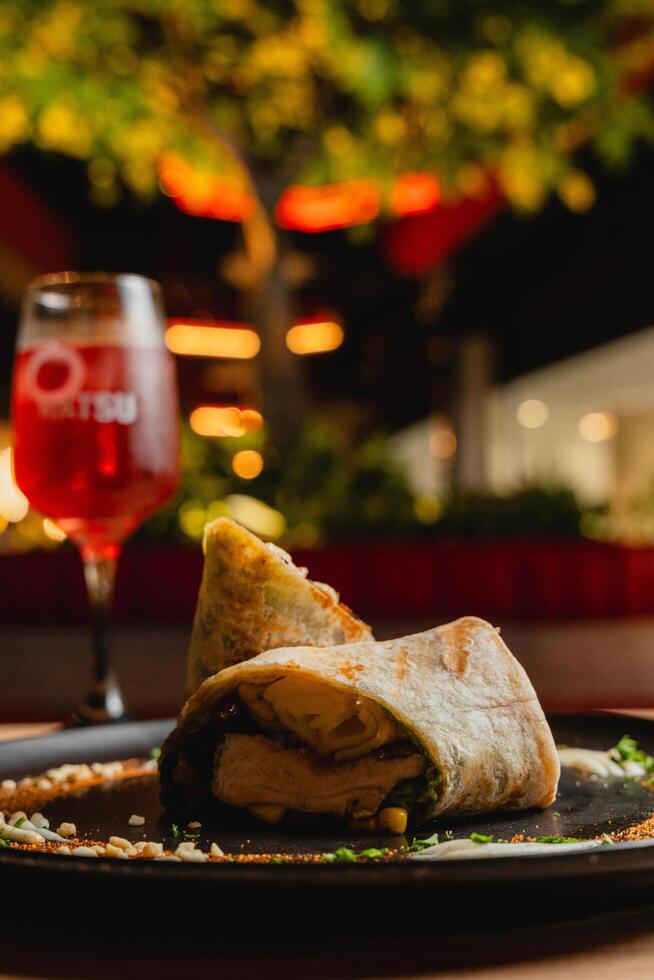 Chicken wrap with sauces, presented on a black plate. photo