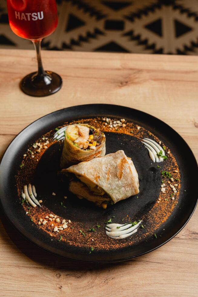 Chicken wrap with sauces, presented on a black plate. photo