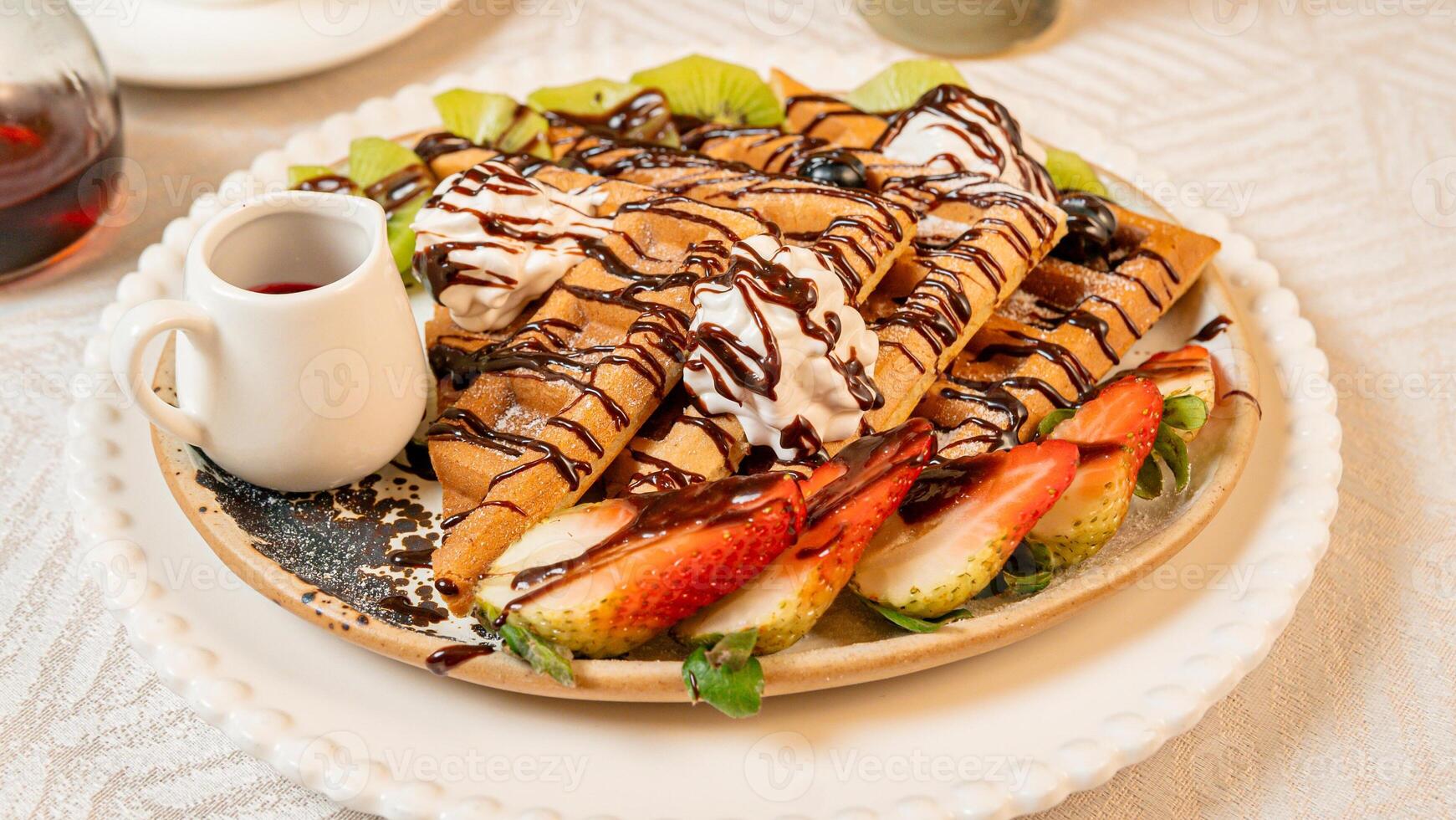 Fruit crepes with chocolate and maple syrup for breakfast photo