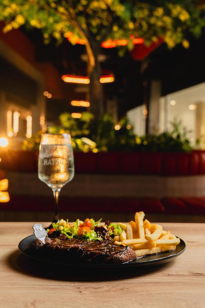 Lunch featuring a steak filet, salad, and French fries, elegantly presented on a table. photo