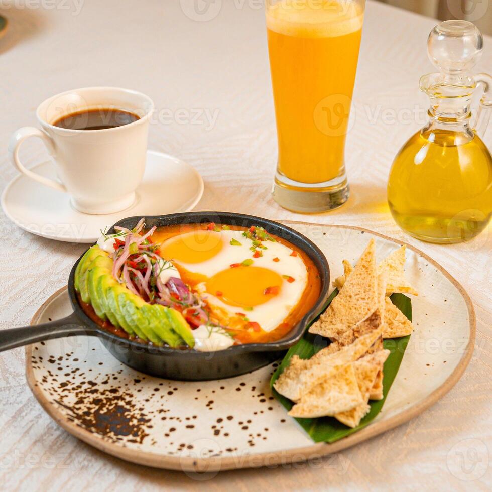 Breakfast with a casserole of sunny-side-up eggs, orange juice, fruits, and avocado photo