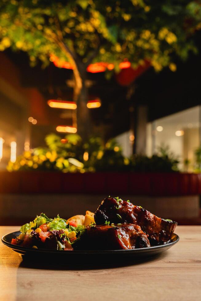 Lunch featuring a steak filet, salad, and French fries, elegantly presented on a table. photo