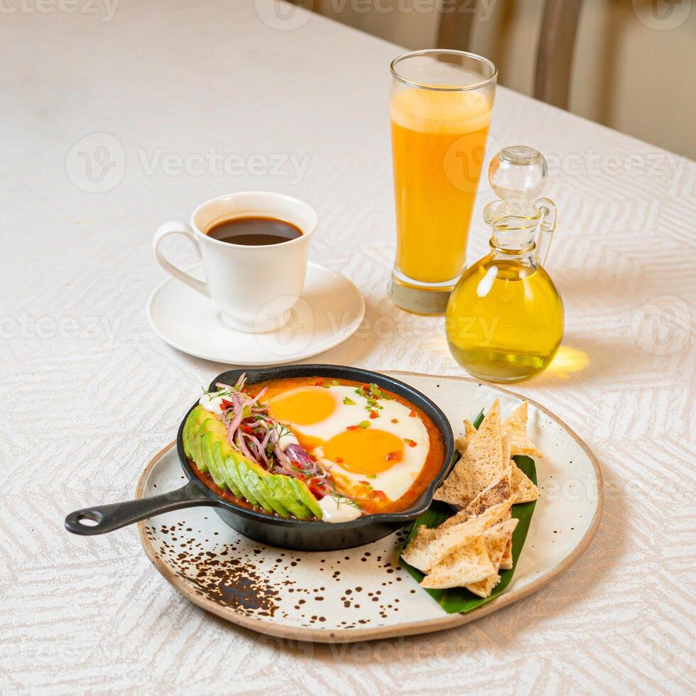 Breakfast with a casserole of sunny-side-up eggs, orange juice, fruits, and avocado photo