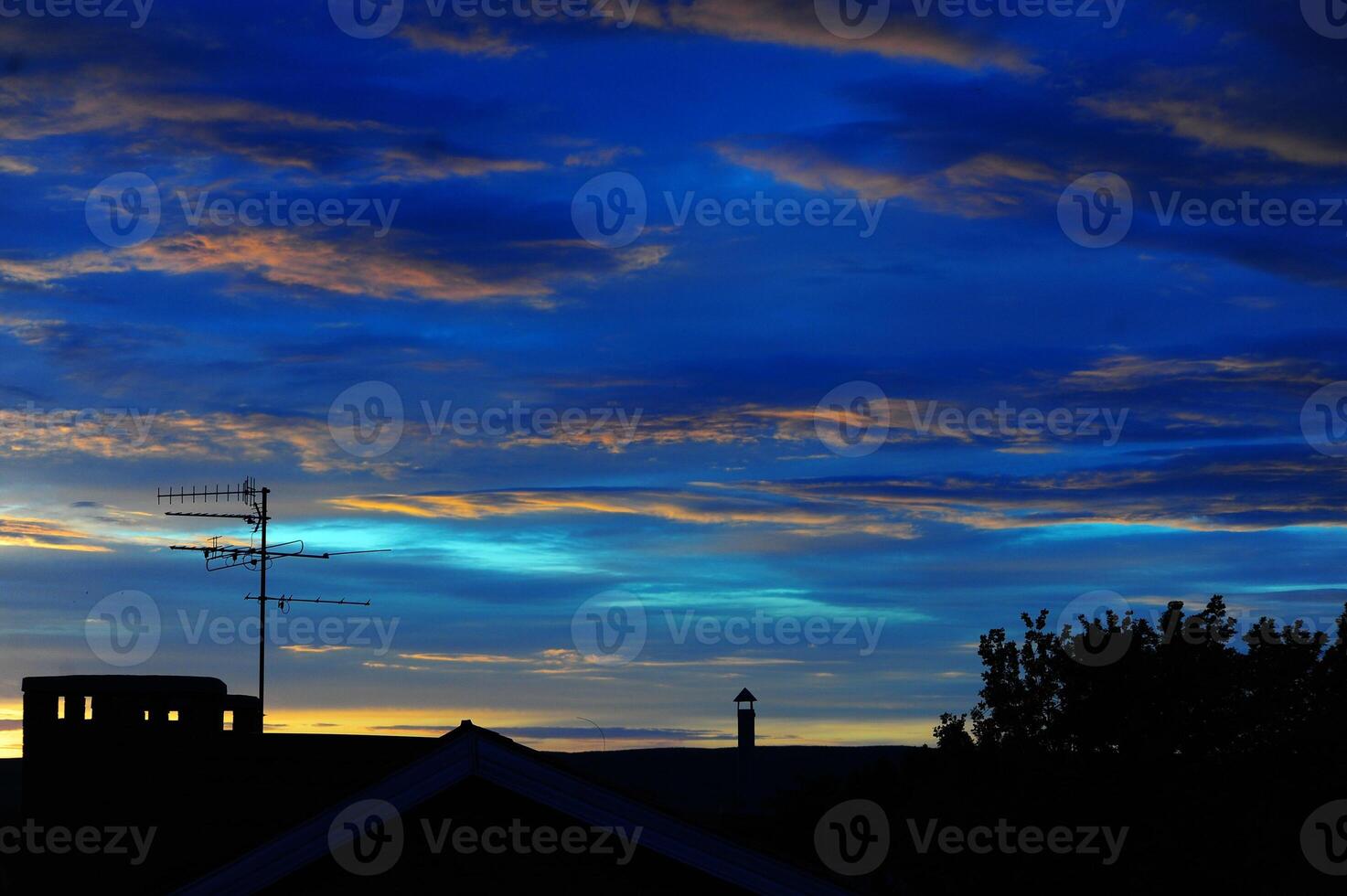 A beautiful house stands silhouetted against a stunning sunset sky photo