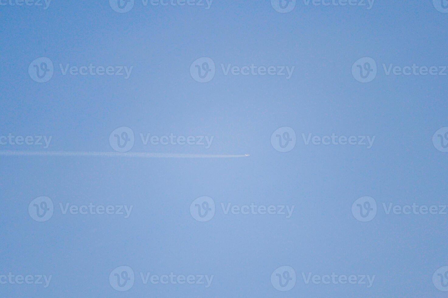 A plane is soaring high while navigating through the clear blue sky photo