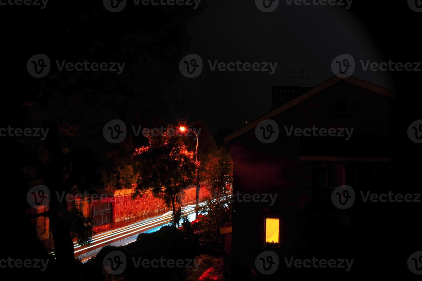 A blurry night street scene with a house in the foreground photo