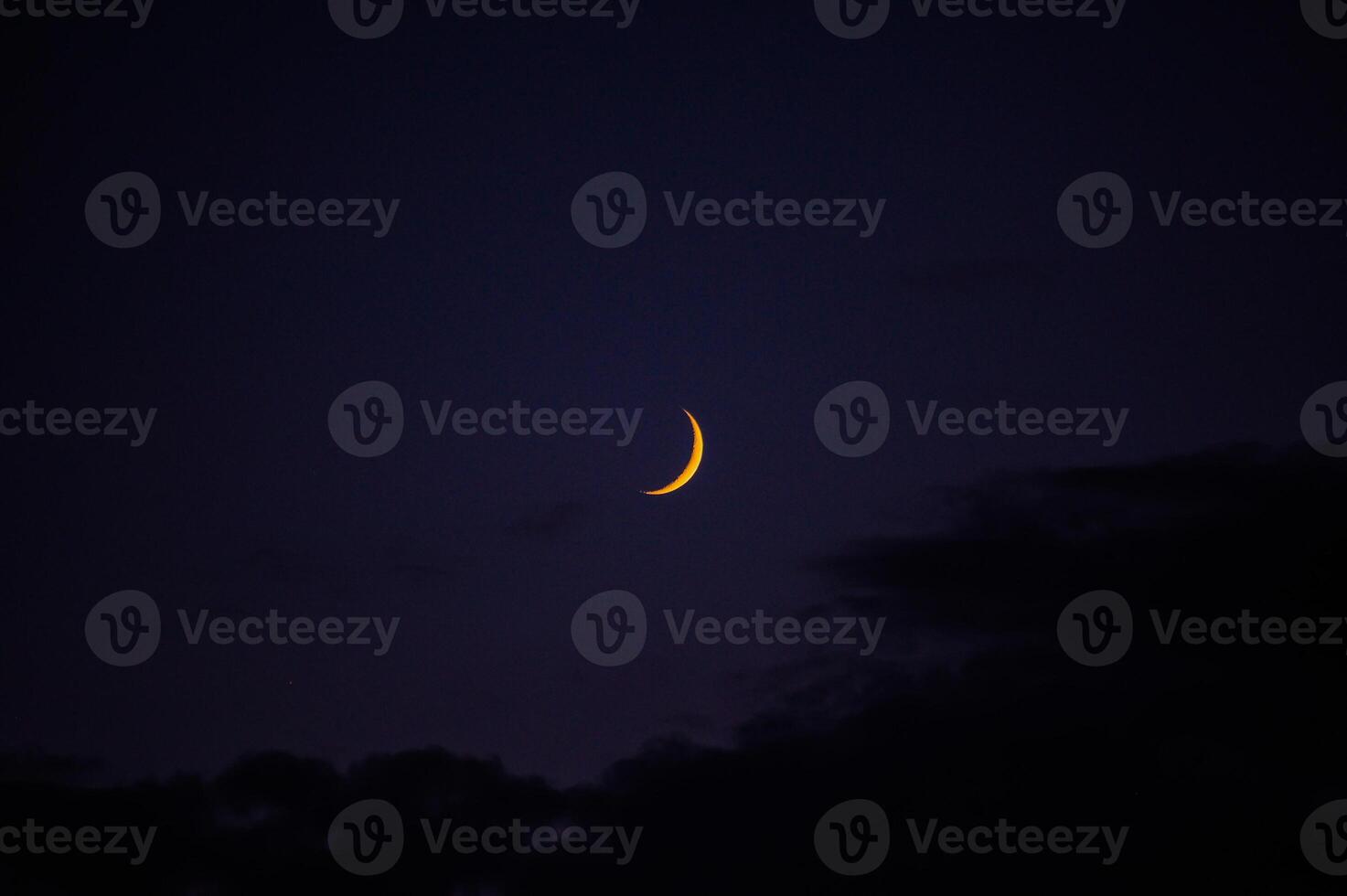 In the dark night sky, a beautiful yellow crescent moon shines bright photo