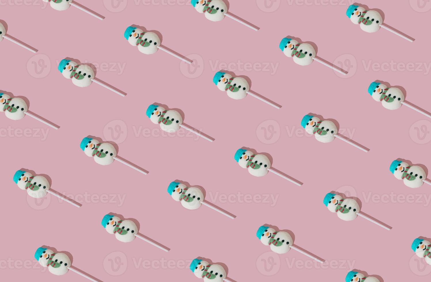 Christmas pattern made with snowman lollipop on pastel pink background. Minimal Christmas and New Year sweet candy concept. Creative festive holiday idea. Winter aesthetic backdrop. photo