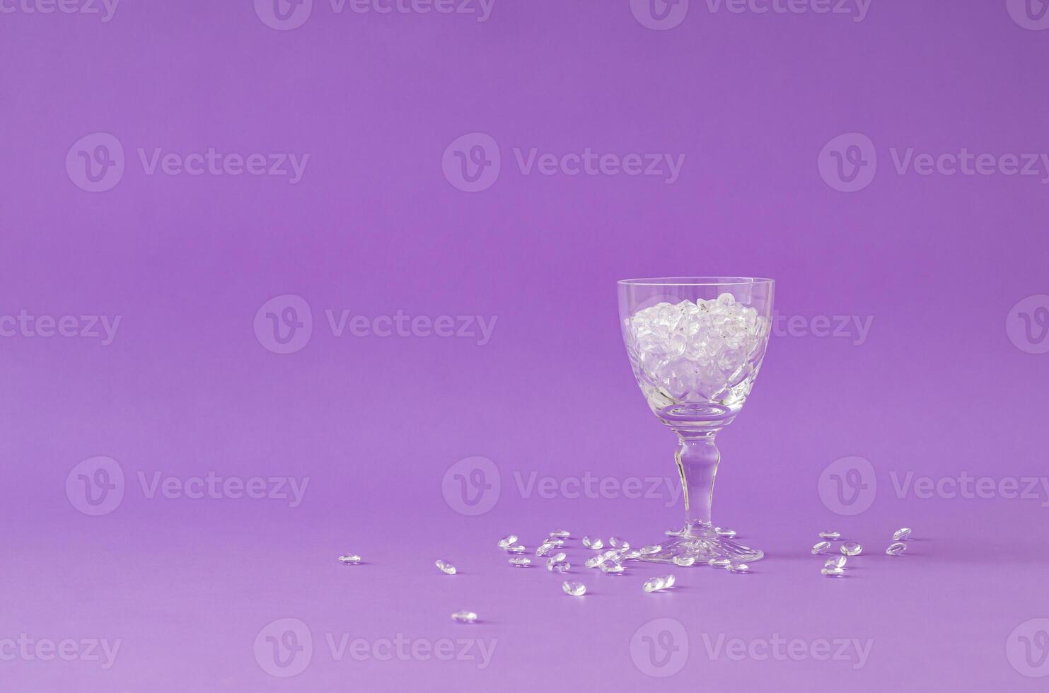 Creative layout made with cocktail glass full of diamonds against purple background. Minimal jewelry retro fashion party concept. Romantic drink idea. photo