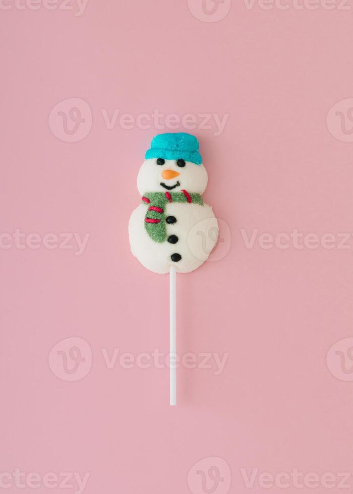 Christmas composition made with snowman lollipop on pastel pink background. Minimal Christmas and New Year sweet candy concept. Creative festive holiday idea. Flat lay, top of view. photo