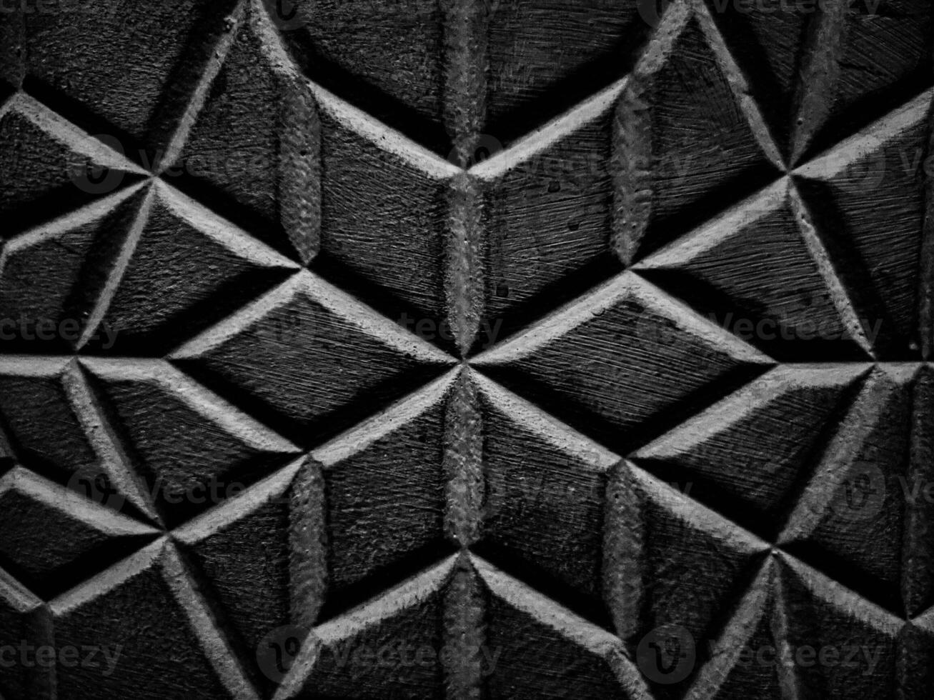A diamond patterned wall with its textured surface and interplay of light and shadow enhancing the geometric design in picturesque black and white thus reveals intricate details in close ups. photo