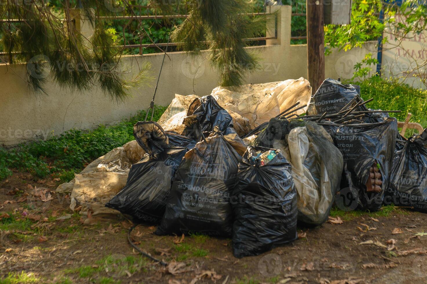 Piles of trash bags awaiting collection in a suburban outdoor setting during daylight hours photo