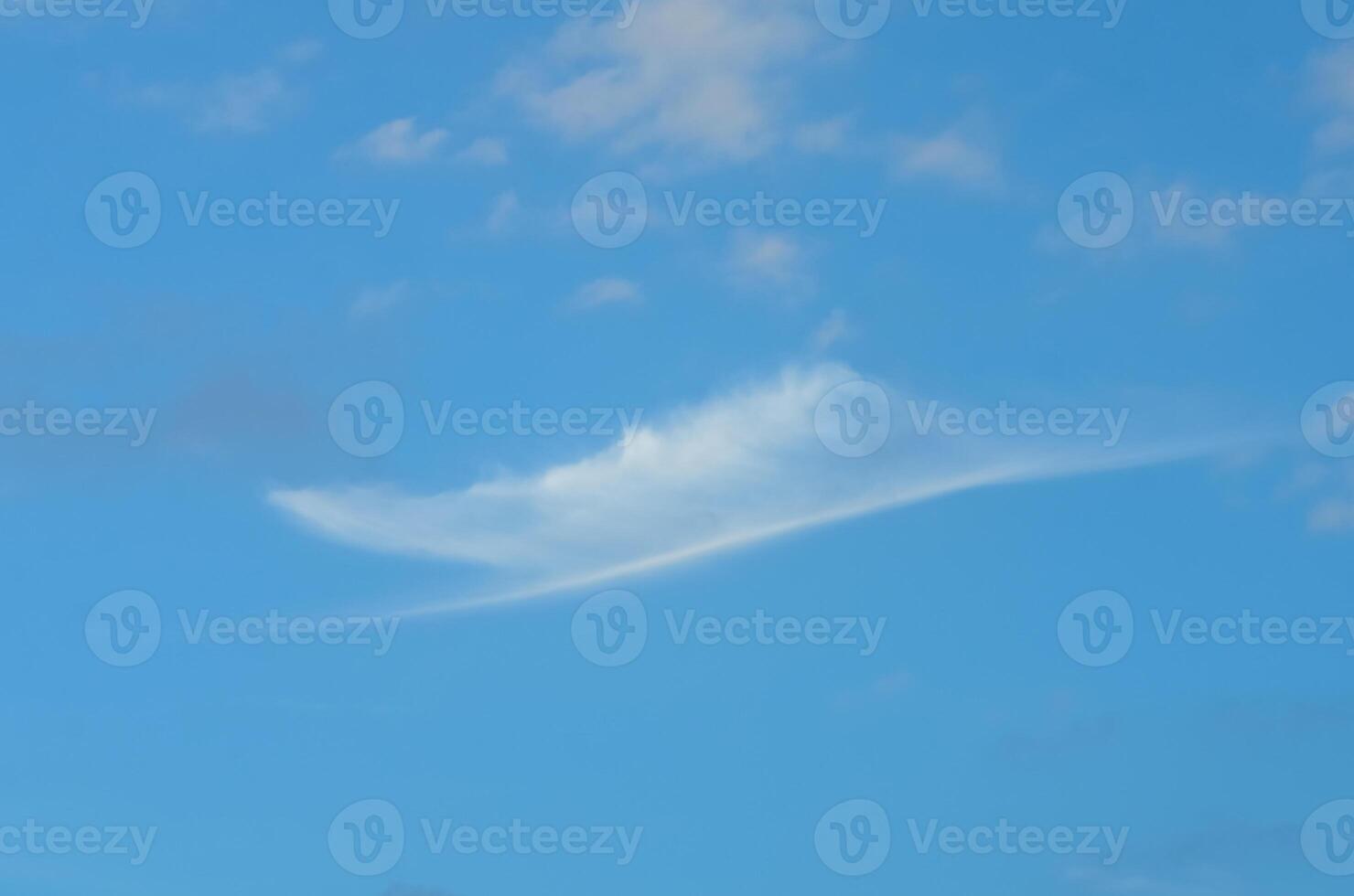 Unique cloud formation resembling a floating sail across the bright blue sky at midday photo